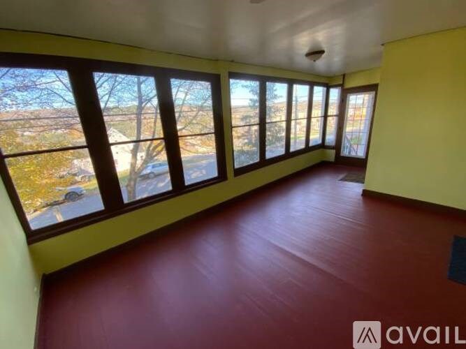 A room with yellow walls and a red floor with large windows.