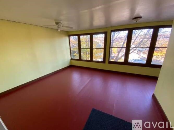 A room with a red floor and yellow walls with a ceiling fan.