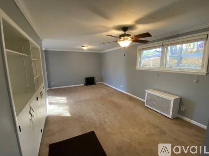 A room with a ceiling fan and a window with blinds.