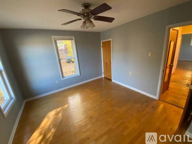 A room with a ceiling fan and wooden flooring.