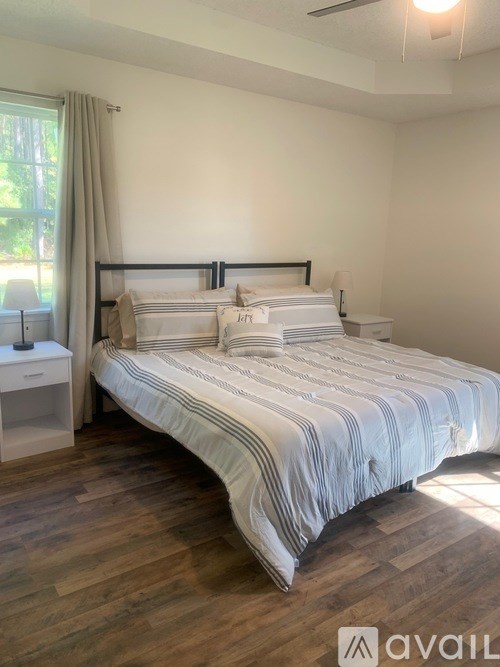 A bedroom with a large bed and wooden flooring.