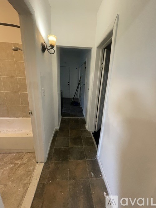 A hallway with a tiled floor and a light on the wall.