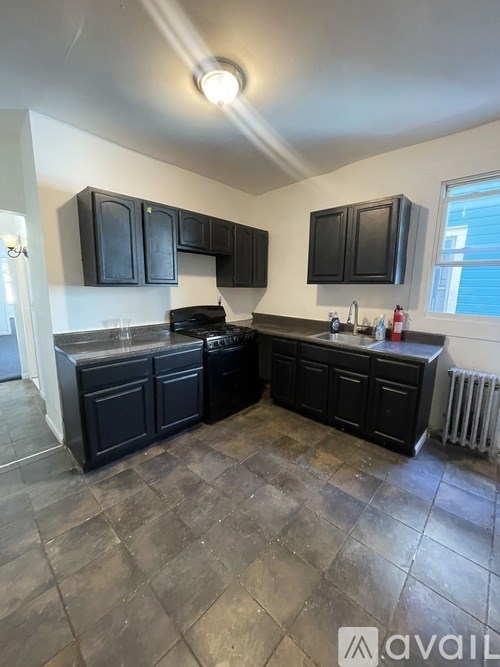 A kitchen with black cabinets and a black dishwasher.