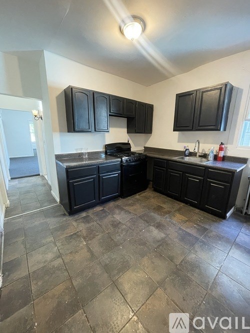 A kitchen with black cabinets and a tile floor.