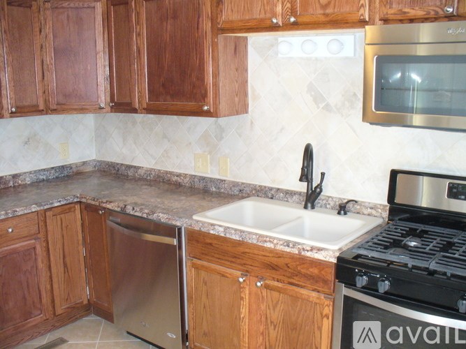 A kitchen with wooden cabinets and a stainless steel dishwasher.