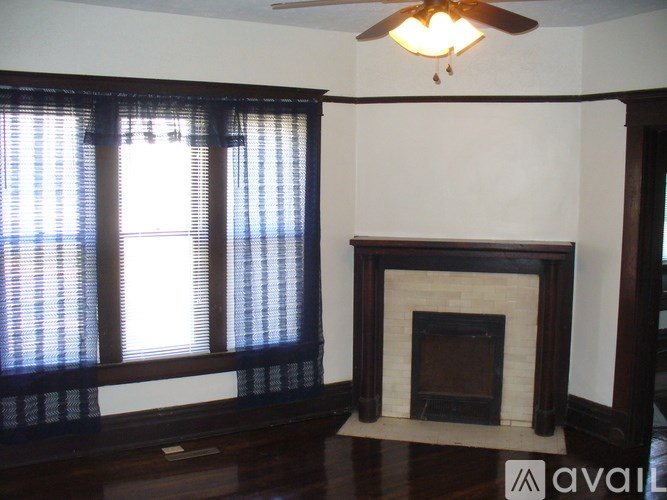 A living room with a fireplace and a ceiling fan.