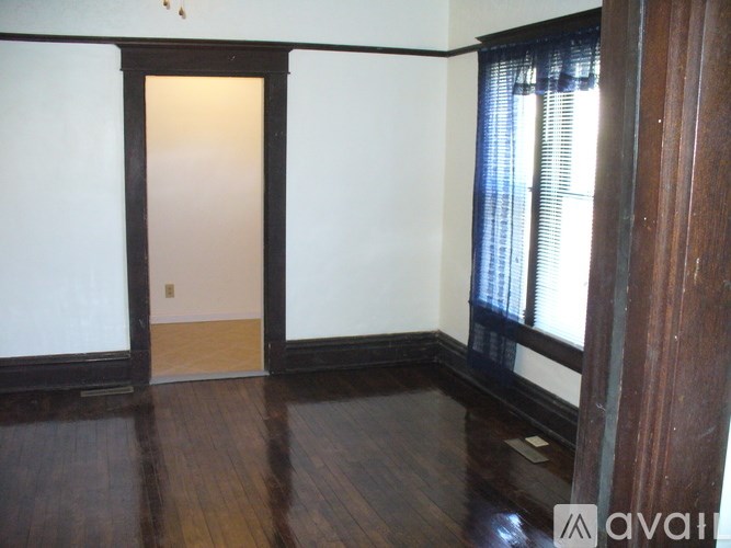 A room with a wooden floor and a doorway leading to another room.