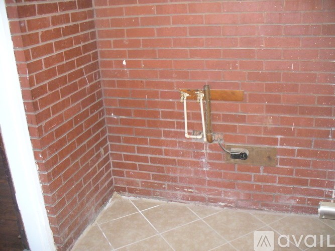 A red brick wall with a white pipe and a wooden board.