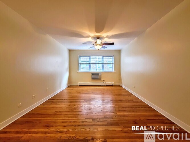 A spacious room with wooden floors and a ceiling fan.
