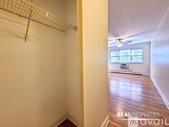A room with a wooden floor and a window with blinds.