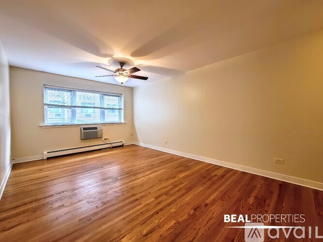 A spacious room with wooden flooring and a ceiling fan.