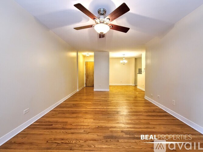 A long hallway with a ceiling fan and wooden floors.