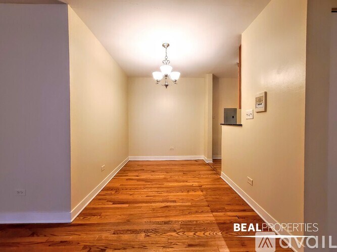 A hallway with wooden floors and a chandelier.