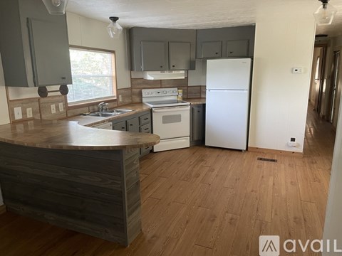 A kitchen with a white refrigerator and wooden floors.