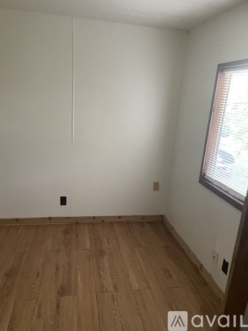 A room with wooden flooring and a window.