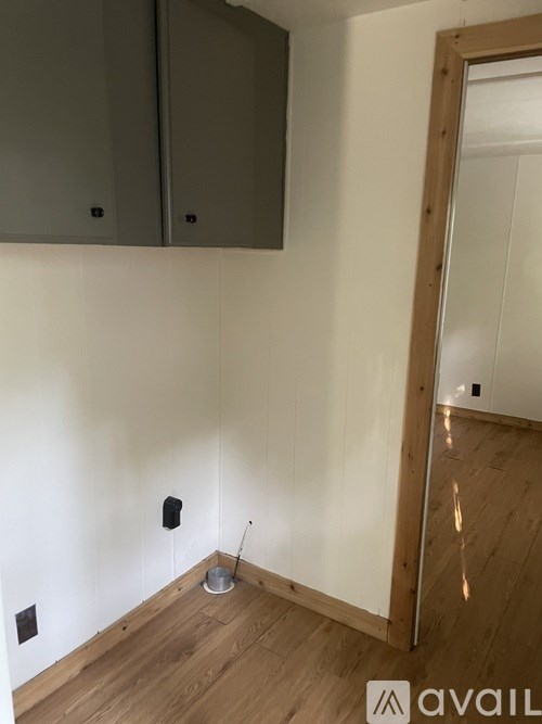 A room with wooden floors and a white wall with a black speaker on it.