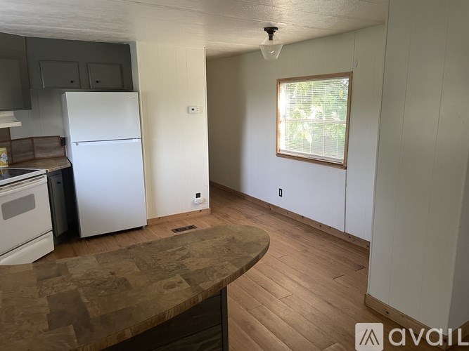 A kitchen with a white fridge and wooden floors.