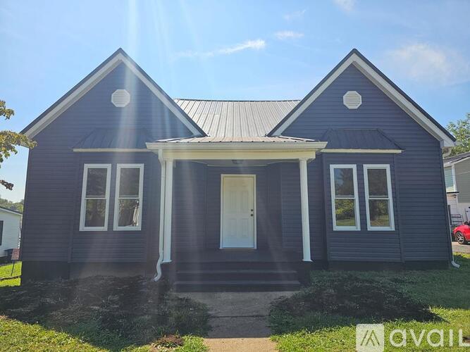 A blue house with a white door and windows is for sale.