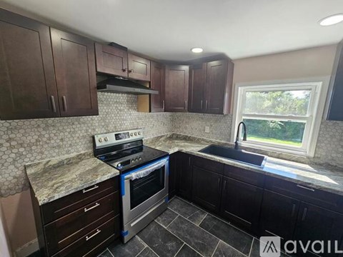 A kitchen with dark wood cabinets and a granite countertop.