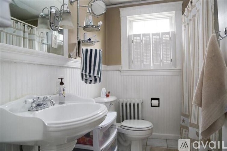 A bathroom with a white sink, toilet, and a window with white blinds.