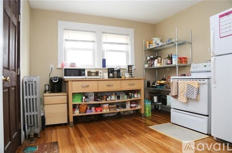 A kitchen with a white fridge, wooden floors, and a window.