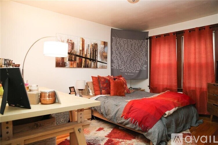 A bedroom with a bed, a desk, and a wall with pictures and a quote.