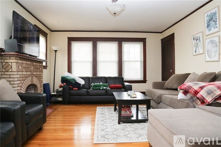 A living room with a black couch, a grey couch, a black coffee table, a fireplace, and a television.