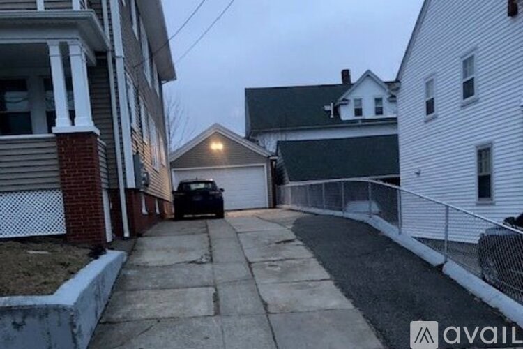 A black car is parked in a driveway between two houses.