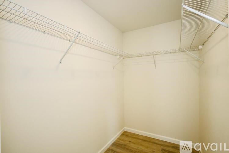 A white wall with a wooden floor and a metal rack on the ceiling.