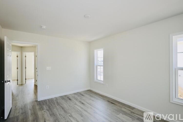 A spacious room with wooden flooring and white walls.