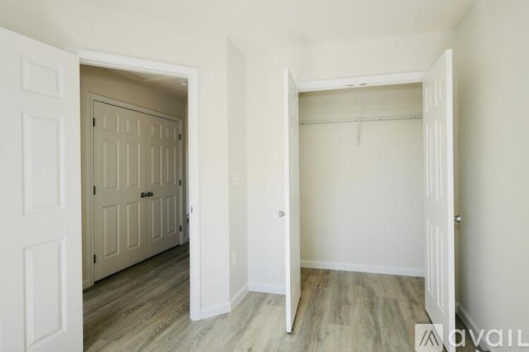 A white door is open to a room with a wooden floor.