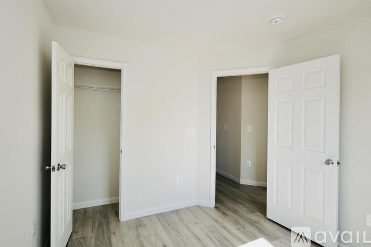 A room with two doors, one open, and a wooden floor.