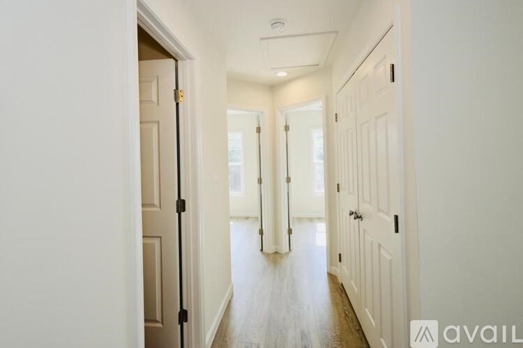 A hallway with white walls and a wooden floor.