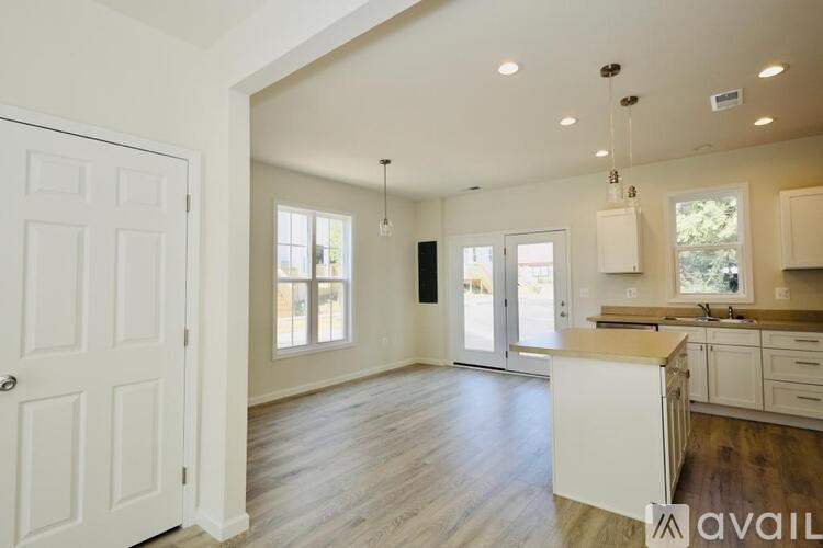A spacious kitchen with white cabinets and a wooden floor.