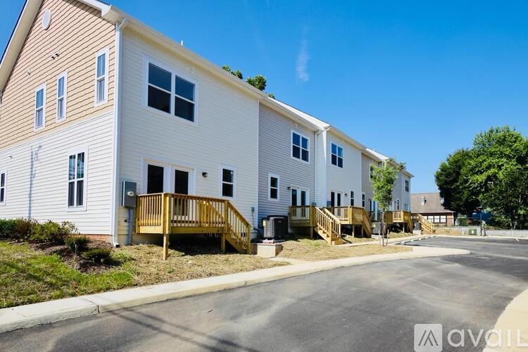 A row of white houses with wooden balconies are lined up on a street.