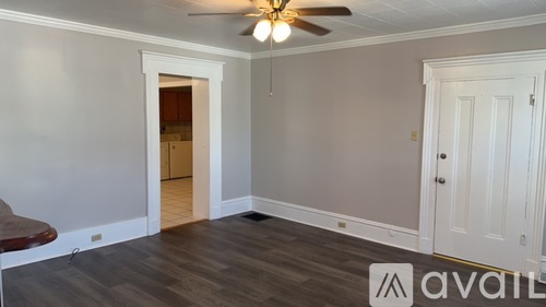 A room with a ceiling fan and a door leading to another room.