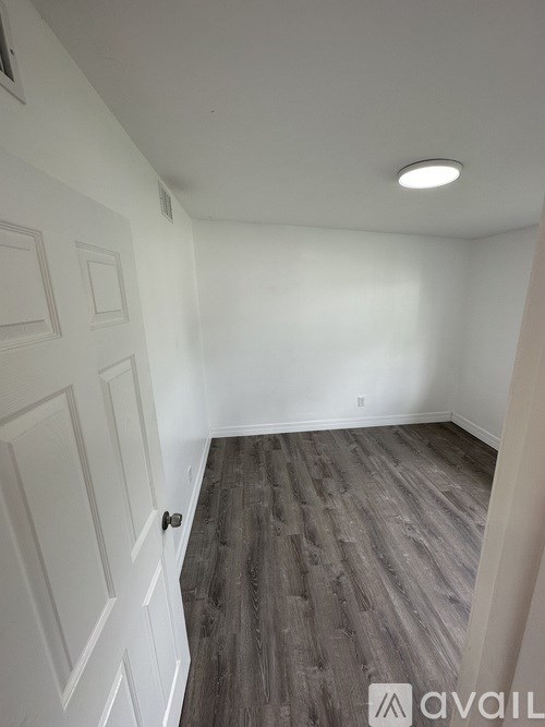 A room with a white door and grey flooring.