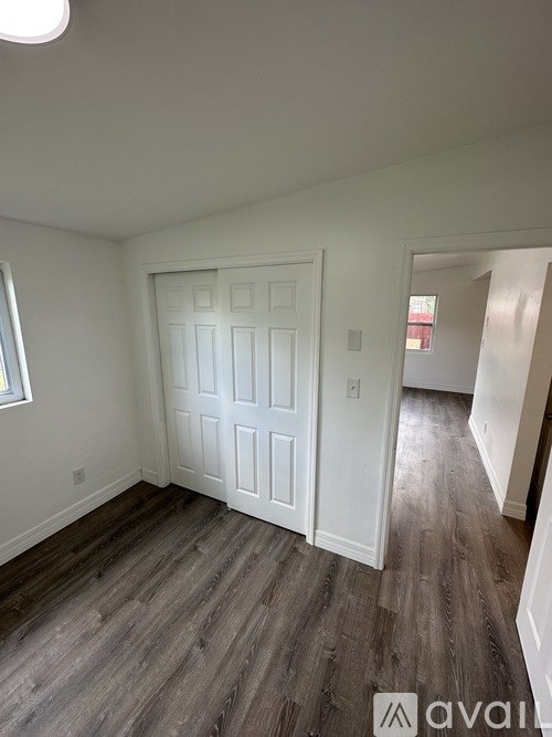 A room with a white door and wooden flooring.