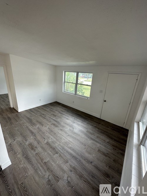 A room with a window and a wooden floor.
