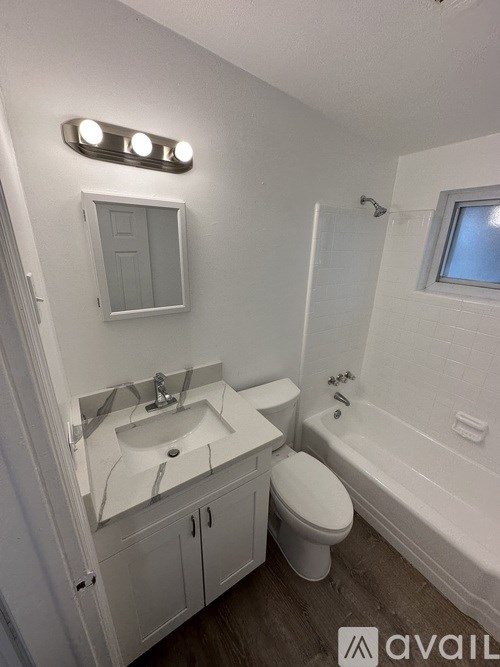 A white bathroom with a toilet, sink, and bathtub.