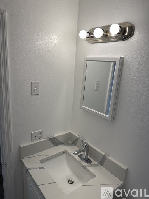 A bathroom with a sink, mirror and lights.