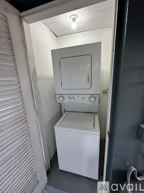 A white washing machine is in a small, dark room.