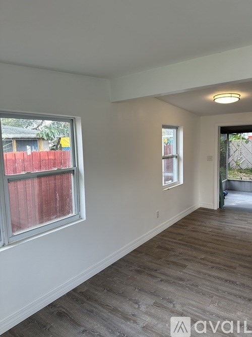 A room with a window and a door leading to a backyard.