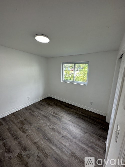 A room with a window and wooden flooring.
