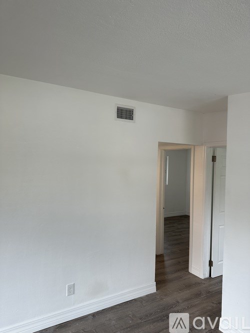 A room with a white wall and a vent.