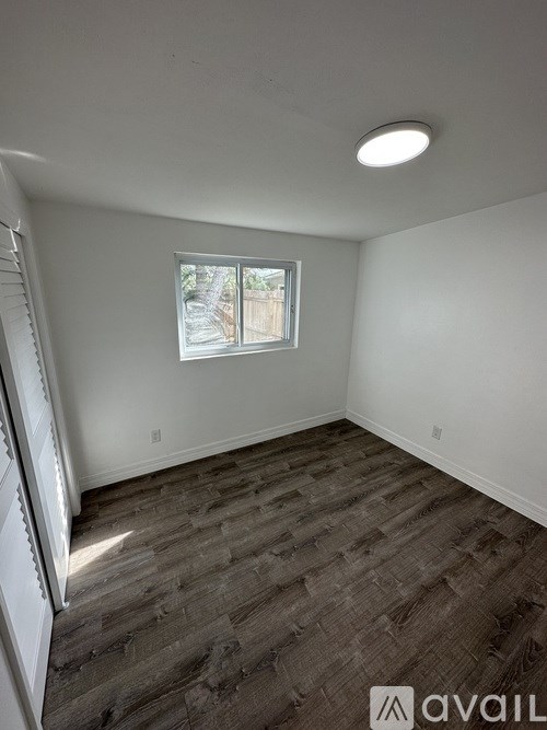 A room with a window and wooden flooring.