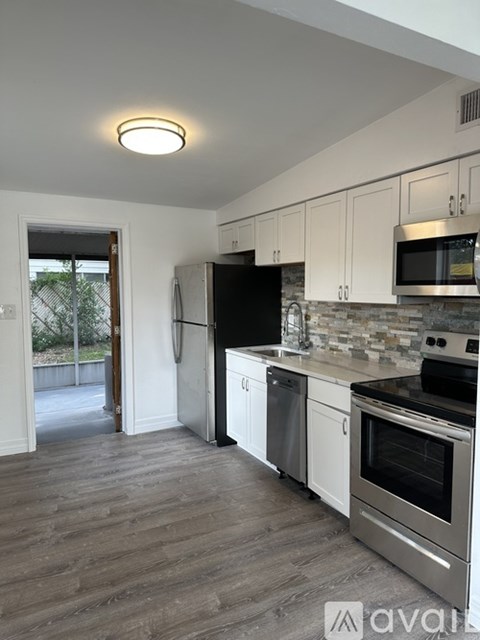 A kitchen with white cabinets and a wooden floor.