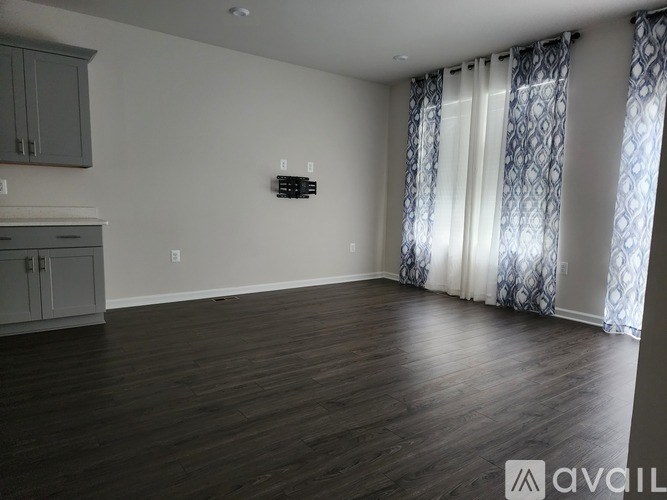 A room with wooden floors and a window with curtains.