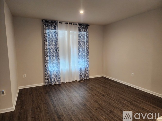 A room with wooden flooring and a window with curtains.