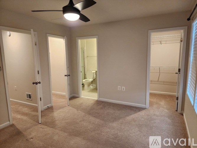 A room with a carpeted floor and a ceiling fan.